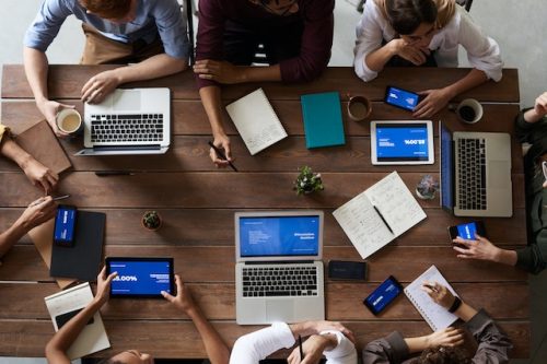 faceless team at a table with laptops and pads